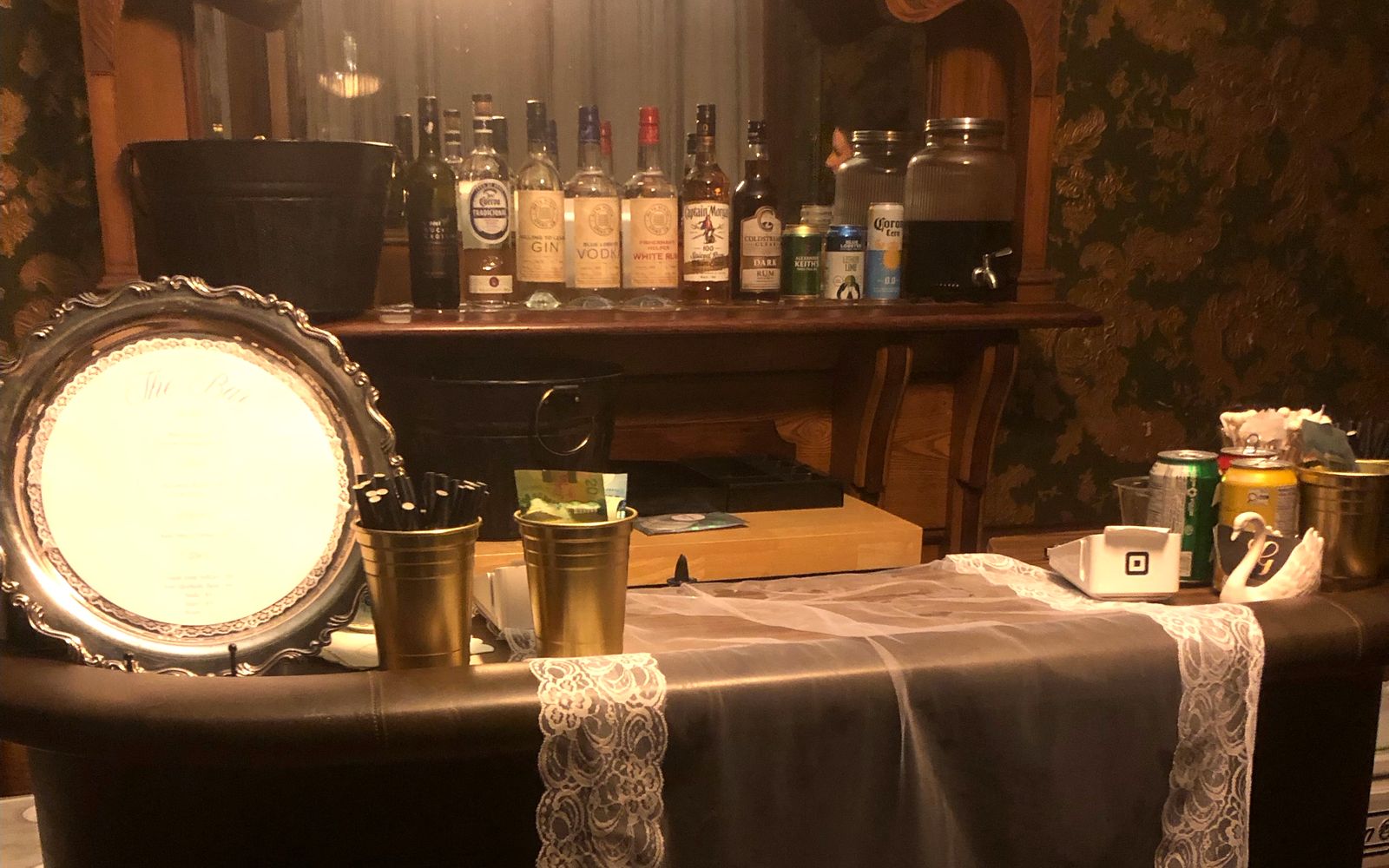 Golden Service mobile bar set up for a wedding, with a stocked back bar, drink menu and signature cocktail banner